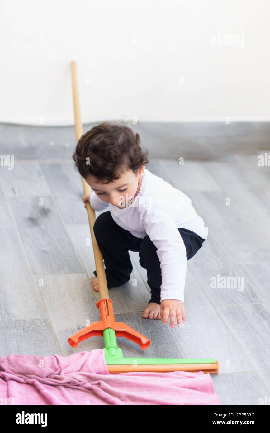 Portrait du sol de carrelage de nettoyage de petit garçon souriant avec  balai à franges et chiffon Photo Stock - Alamy