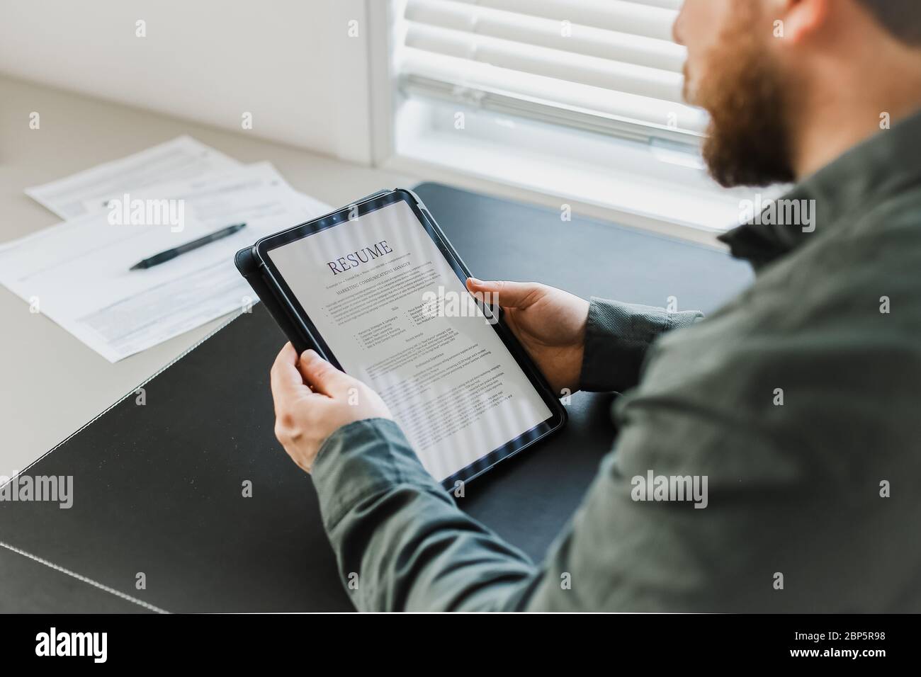 Le demandeur d'emploi examine le CV électronique sur la tablette. Banque D'Images