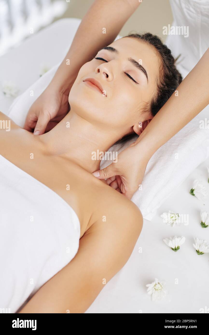 Jeune femme souriante profitant d'un massage relaxant des épaules au spa Banque D'Images