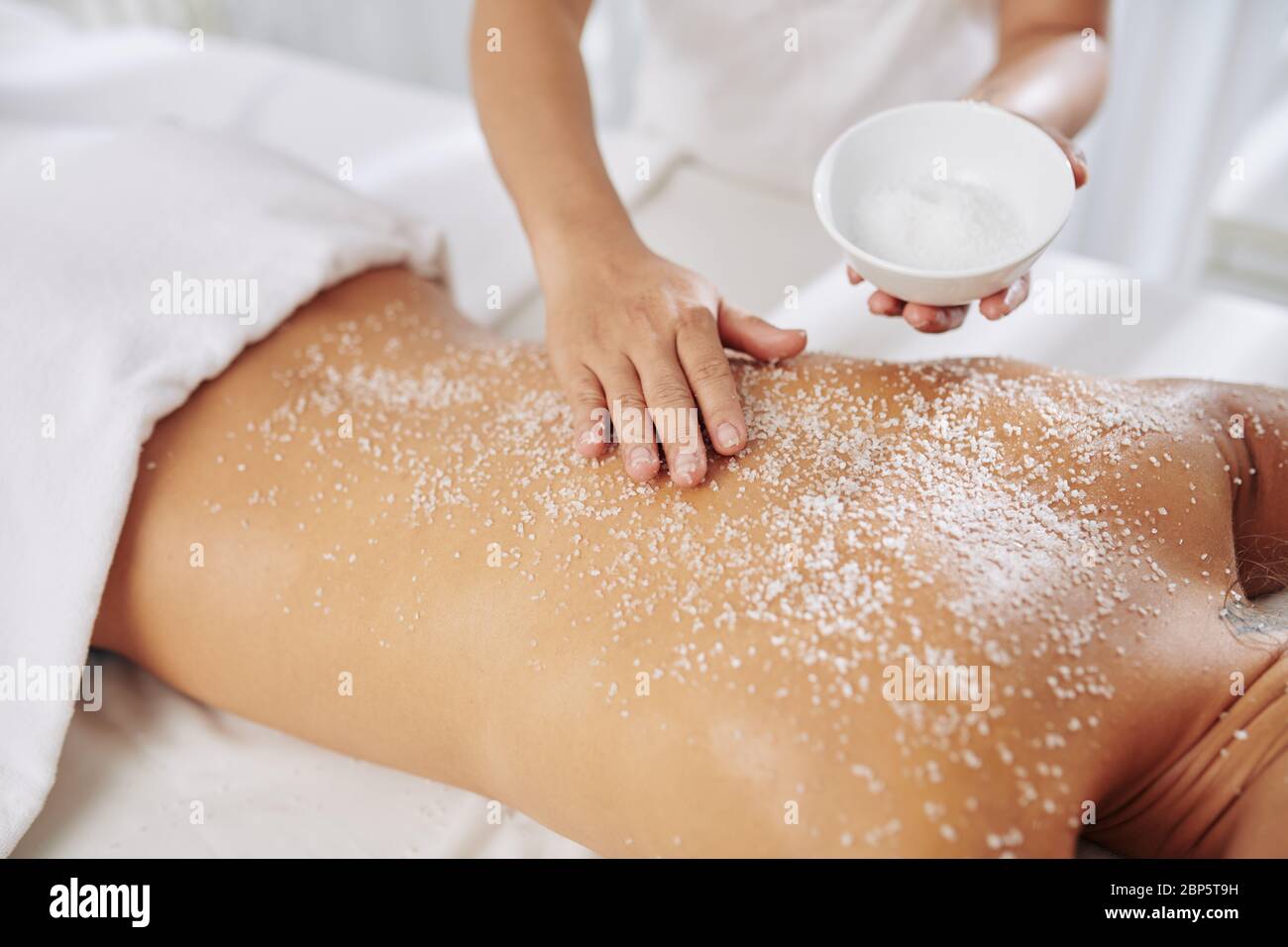 Esthéticienne exfoliant le dos de la jeune femme avec le sel de gommage  avant le massage Photo Stock - Alamy