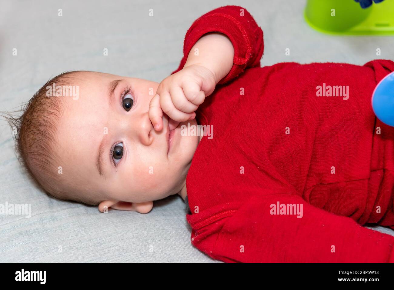 Adorable petit garçon de 6 mois sur le dos entouré de jouets colorés Banque D'Images