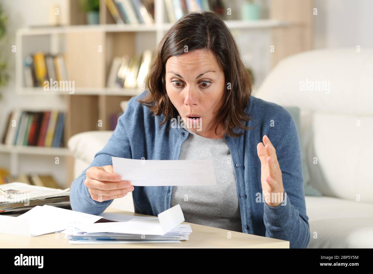 Une femme adulte surprise vérifie les lettres de reçu dans le salon à la maison Banque D'Images