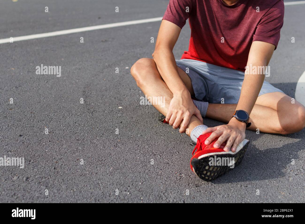 Homme de sport tenant la cheville dans la douleur en raison de la cheville entornée. Blessures dues au concept d'entraînement Banque D'Images
