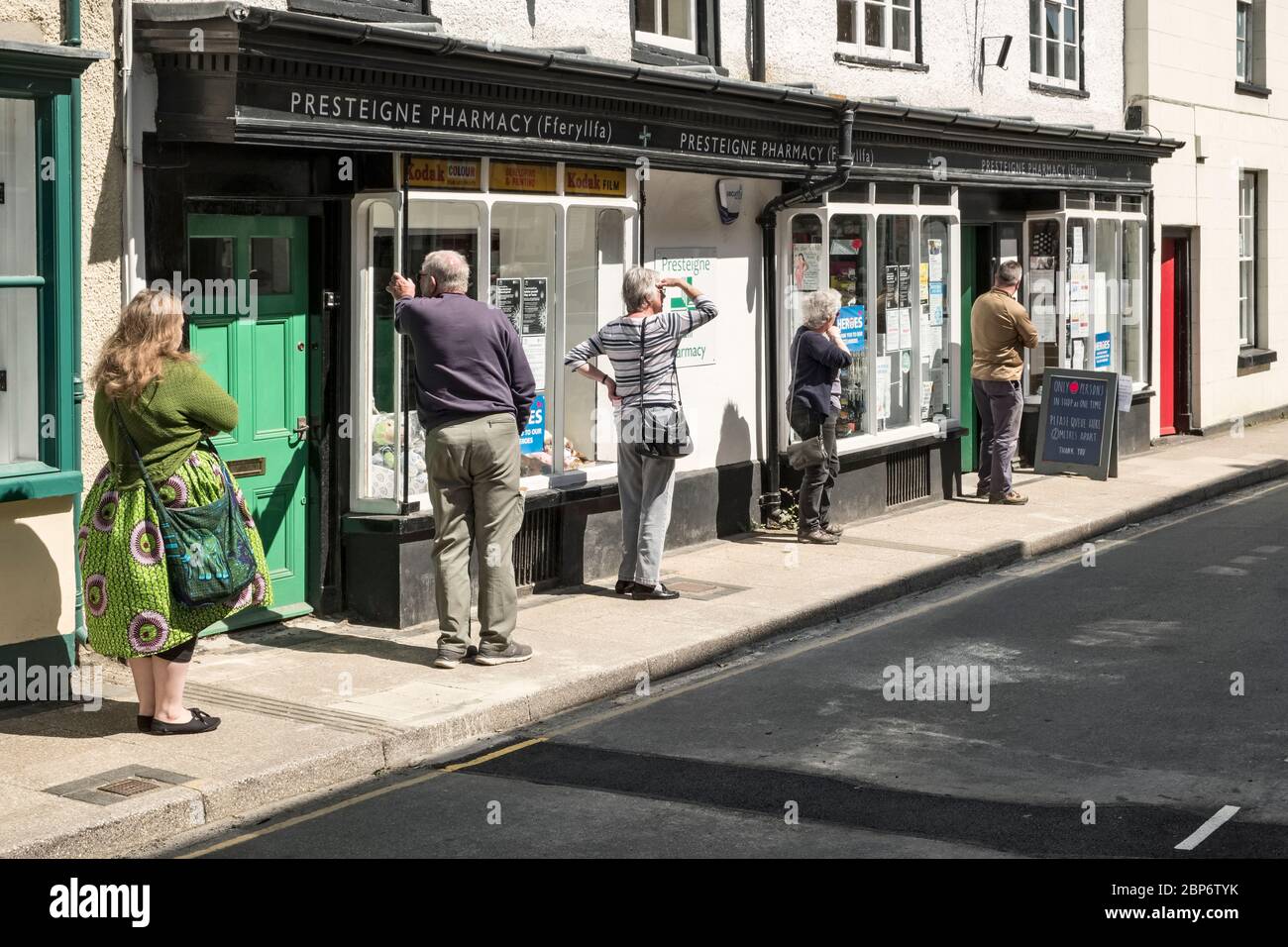 Une file d'attente pour maintenir des distances sociales sûres en dehors de la pharmacie locale dans la petite ville galloise de Presteigne, Powys, Pays de Galles, Royaume-Uni Banque D'Images