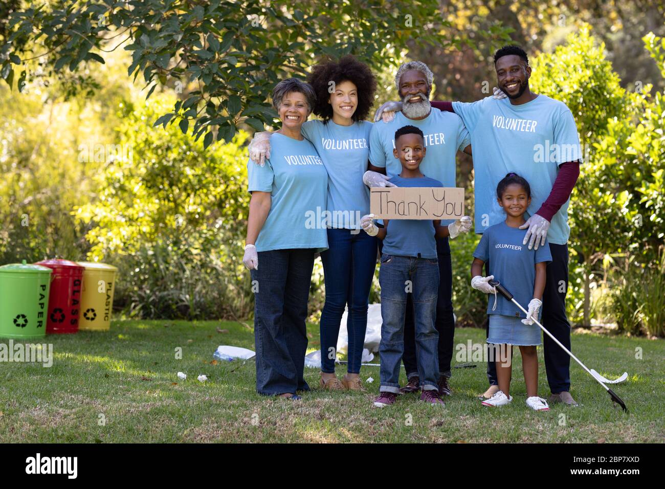 Famille de plusieurs générations collectant des ordures avec un garçon tenant un signe écrit Merci Banque D'Images