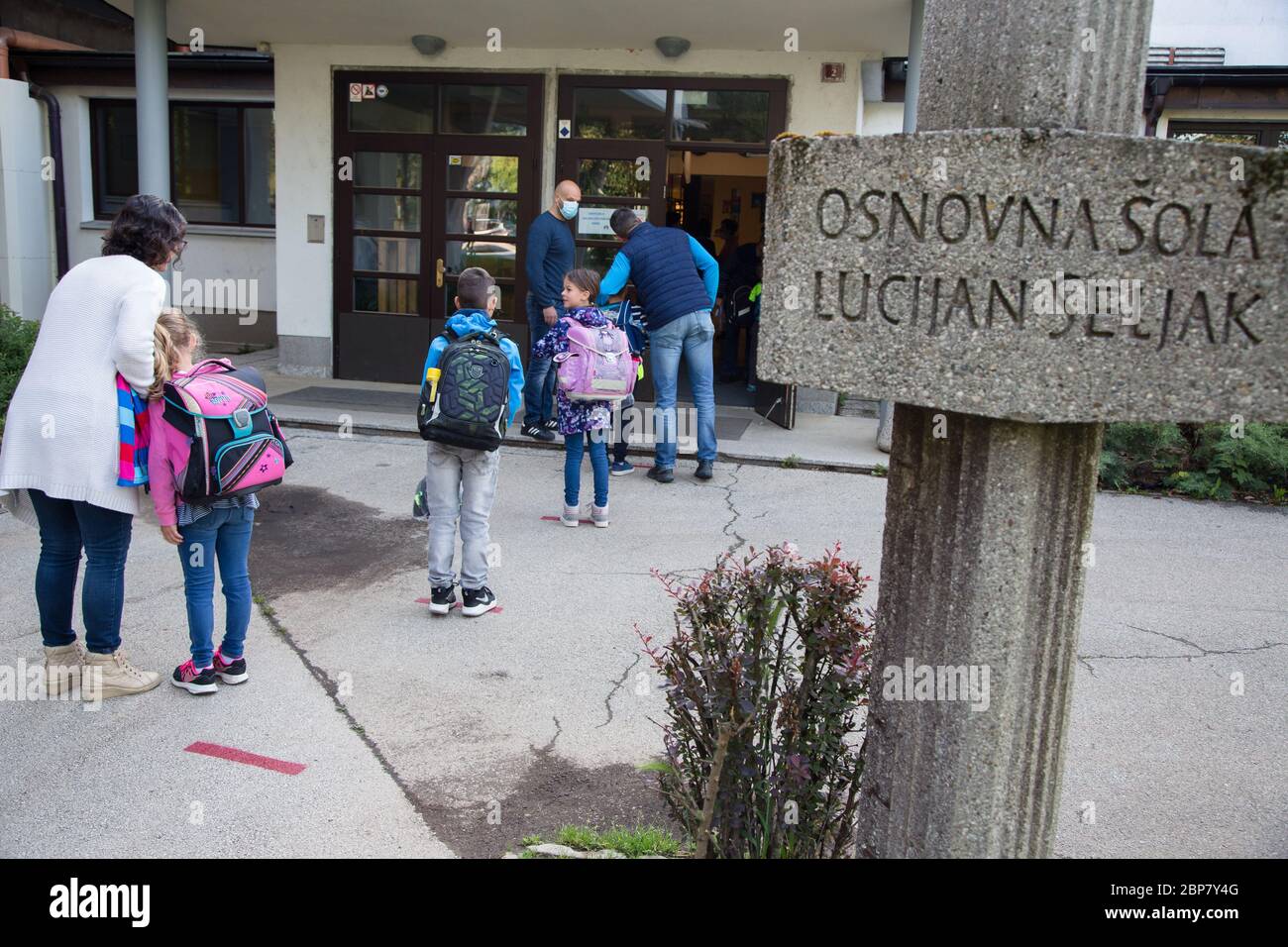 Les enfants attendent à une distance sécuritaire les uns des autres pour entrer dans une école primaire.les élèves des trois premières années de l'école primaire ainsi que les élèves de la dernière année de l'école secondaire en Slovénie retournent dans les écoles après deux mois d'isolement dû à l'épidémie du coronavirus (Covid-19). Banque D'Images