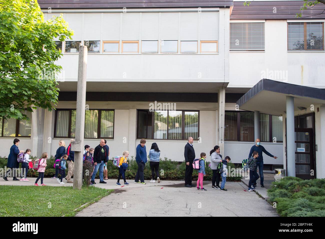 Les enfants et leurs parents attendent à distance de sécurité avant d'entrer dans une école primaire.les élèves des trois premières années de l'école primaire ainsi que les élèves de la dernière année de l'école secondaire en Slovénie retournent dans les écoles après deux mois d'isolement dû à l'épidémie du coronavirus (Covid-19). Banque D'Images