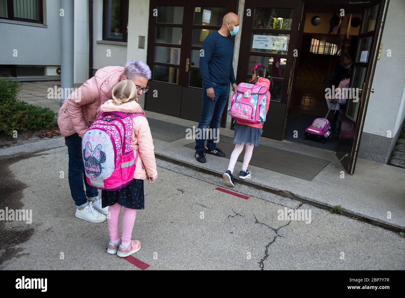 Une fille embrasse sa mère au revoir alors qu'elle attend à une distance sûre pour entrer dans une école primaire.les élèves des trois premières années de l'école primaire ainsi que les élèves de la dernière année de l'école secondaire en Slovénie retournent dans les écoles après deux mois de confinement dû à l'épidémie de coronavirus (Covid-19). Banque D'Images