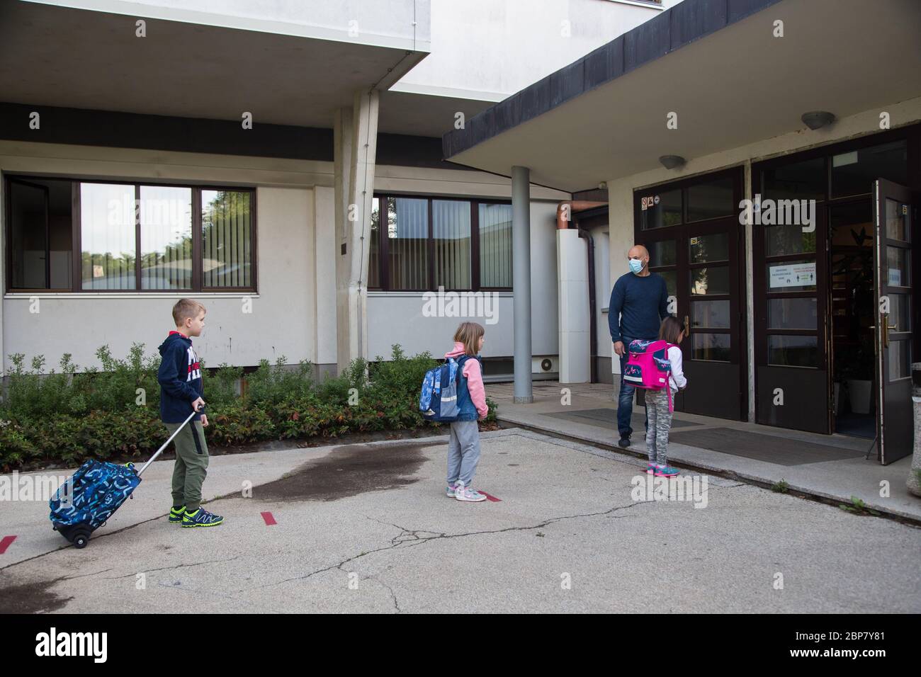 Les enfants attendent à des endroits désignés pour respecter la distance de sécurité avant d'entrer dans une école primaire.les élèves des trois premières années d'école primaire ainsi que les élèves de la dernière année d'école secondaire en Slovénie retournent dans les écoles après deux mois d'isolement dû à l'épidémie du coronavirus (Covid-19). Banque D'Images