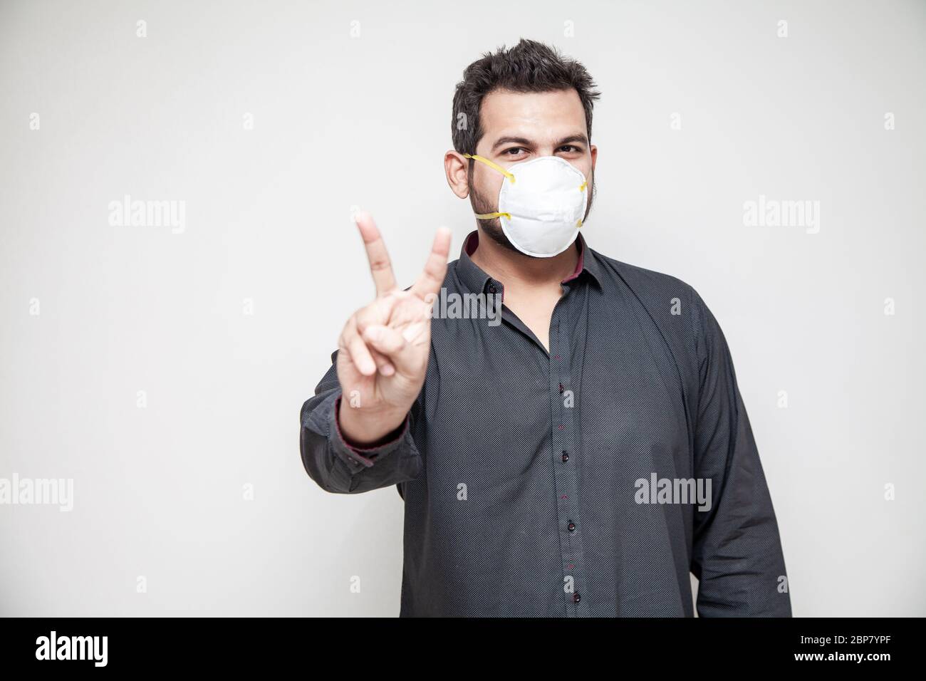 Homme couvrant son visage avec un masque Covid-19, un environnement de travail sûr signe de victoire Banque D'Images