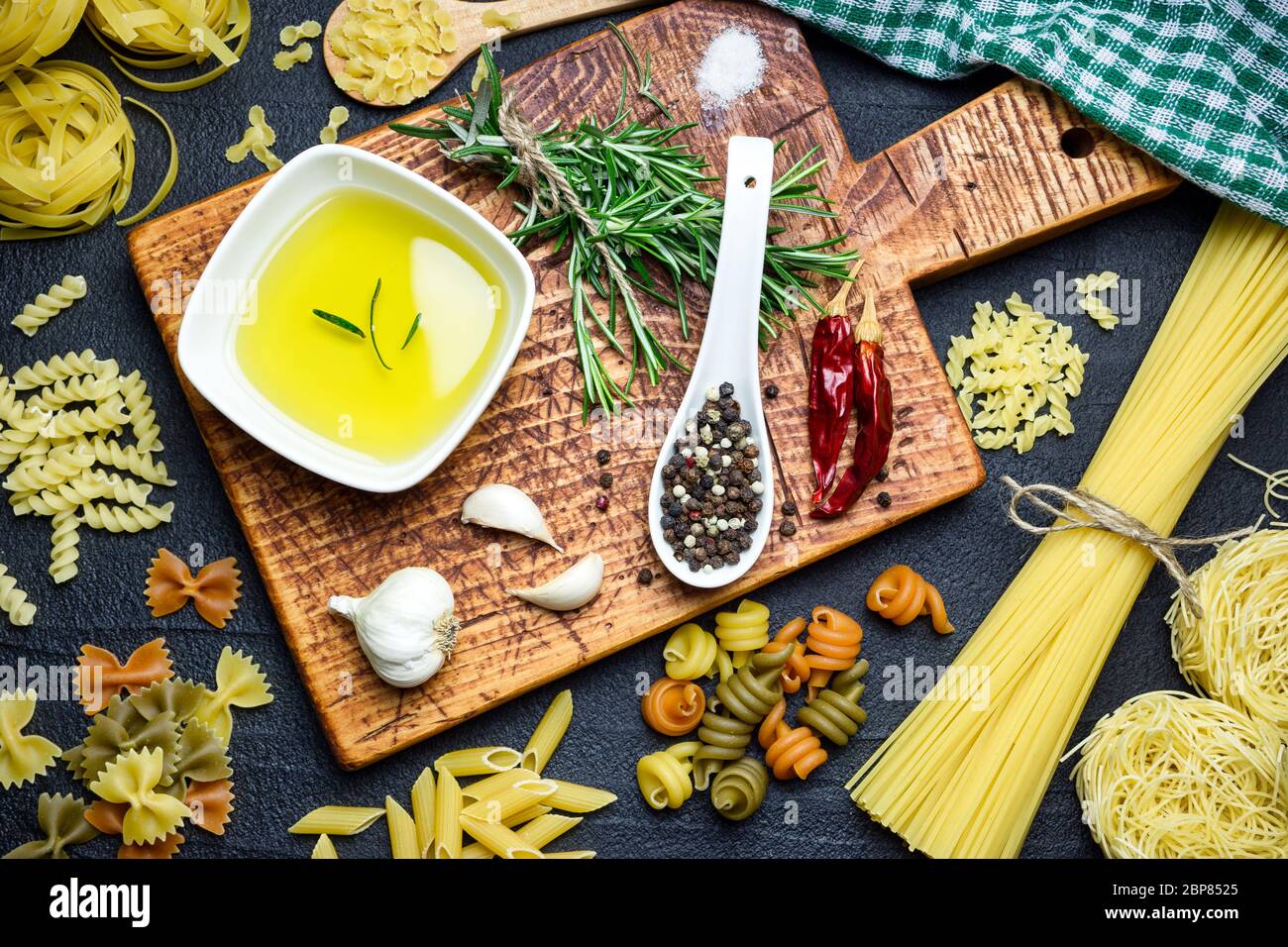 Ingrédients pour la cuisine italienne, pâtes, herbes, épices et huile d'olive sur table en pierre noire, vue du dessus. Banque D'Images