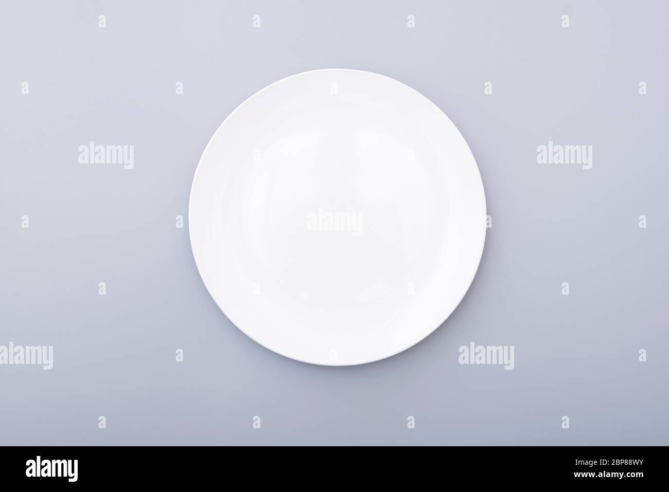 Plaque en céramique blanche sur table grise, vue de dessus de la plaque blanche. Assiette ronde, bol. Banque D'Images