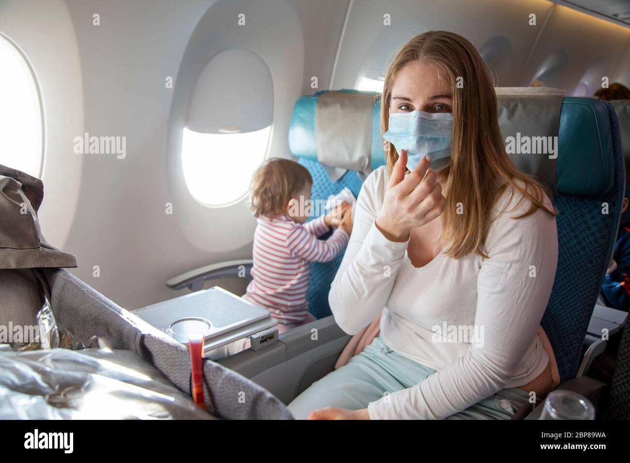 concept peur de voyager à cause du coronavirus covid-19..une jeune mère est  assise dans une chaise d'avion dans un masque respiratoire médical et  éternue Photo Stock - Alamy