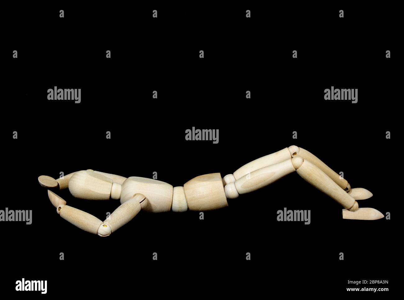 marionnette en bois pendant l'exercice de yoga Ansanas, exercice de muscle abdominal, devant le fond noir Banque D'Images