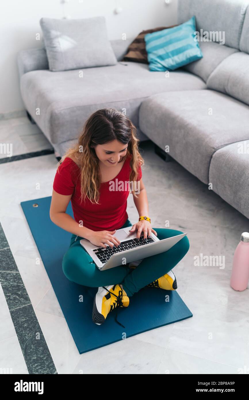 femme faisant du sport sur un tapis suivant des cours en ligne avec un ordinateur portable à la maison Banque D'Images