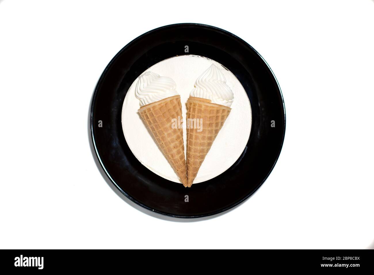 Dessert Blanc Rond Isole Gateau Doux Et Delicieux A La Glace Avec Decoration Deux Cornets De Glace Dans Une Tasse A Gaufres Sur Une Assiette Noire Vue De Dessus Gros Plan Photo