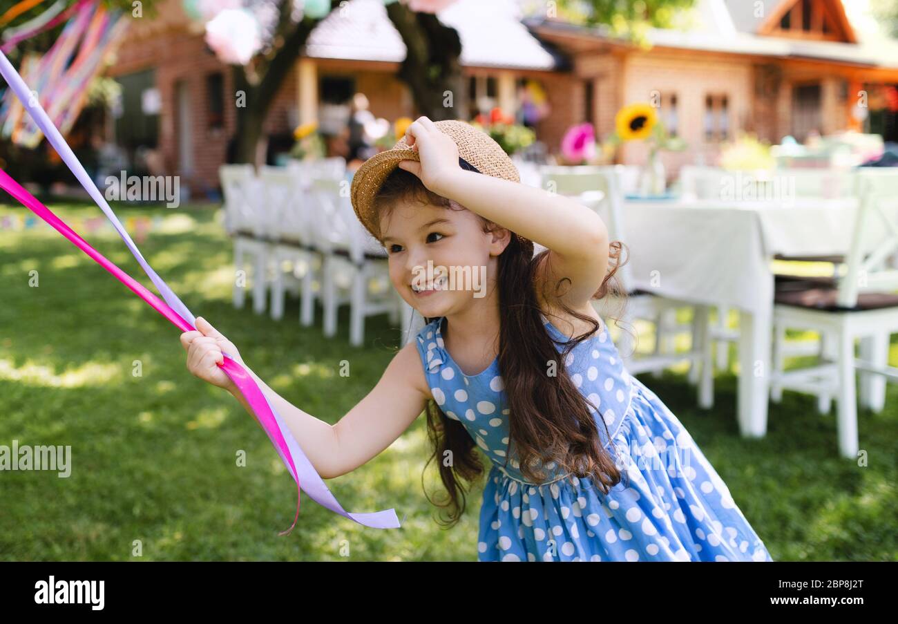 Petite fille à l'extérieur dans le jardin en été, jouant avec des ballons. Banque D'Images