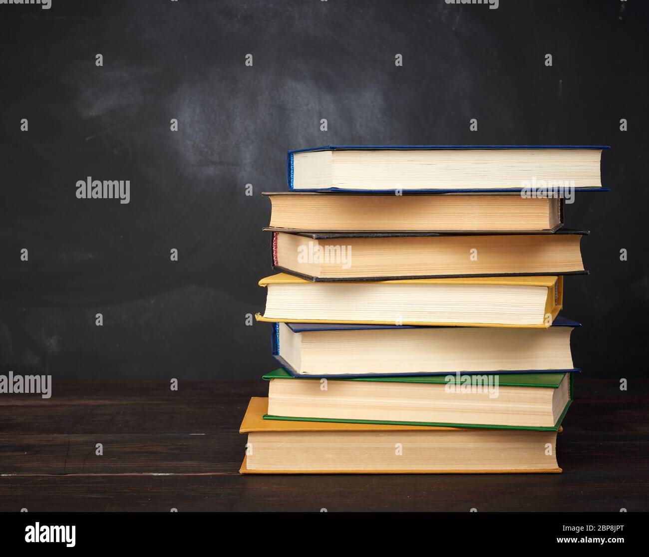 pile de divers livres de hardback sur le fond d'un tableau noir vide de craie, place pour le texte, de retour à l'école Banque D'Images