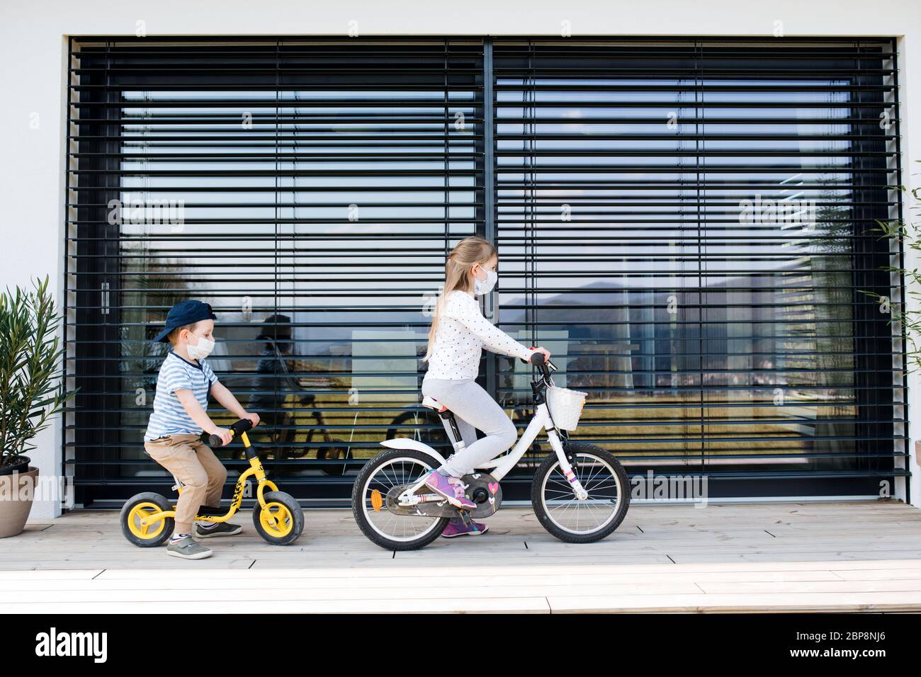 Petite fille et garçon avec des vélos à l'extérieur à la maison. Virus Corona et concept de quarantaine. Banque D'Images