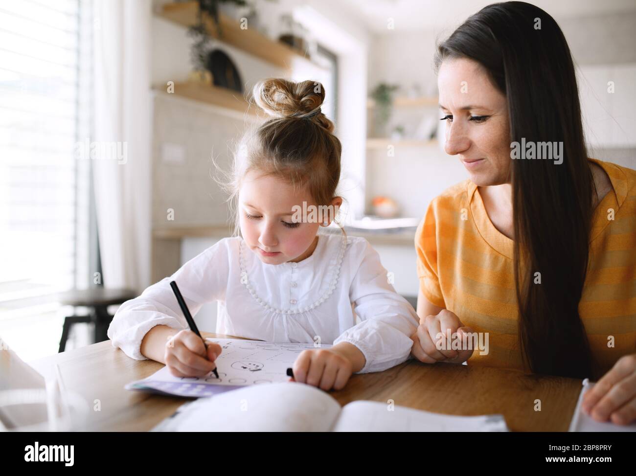 Mère et fille apprenant à l'intérieur à la maison, virus Corona et concept de quarantaine. Banque D'Images