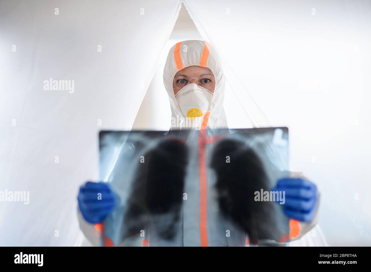 Médecin avec combinaison protectrice et poumons rayons X à l'hôpital, concept coronavirus. Banque D'Images