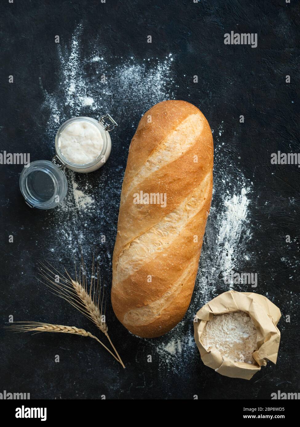 Pain de pain de Bomer blanc britannique ou de levain européen sur fond noir. Pain frais et pot en verre avec démarreur de levain, flotteur dans un sac en papier et oreilles. Vue de dessus. Copier l'espace. Verticale. Banque D'Images
