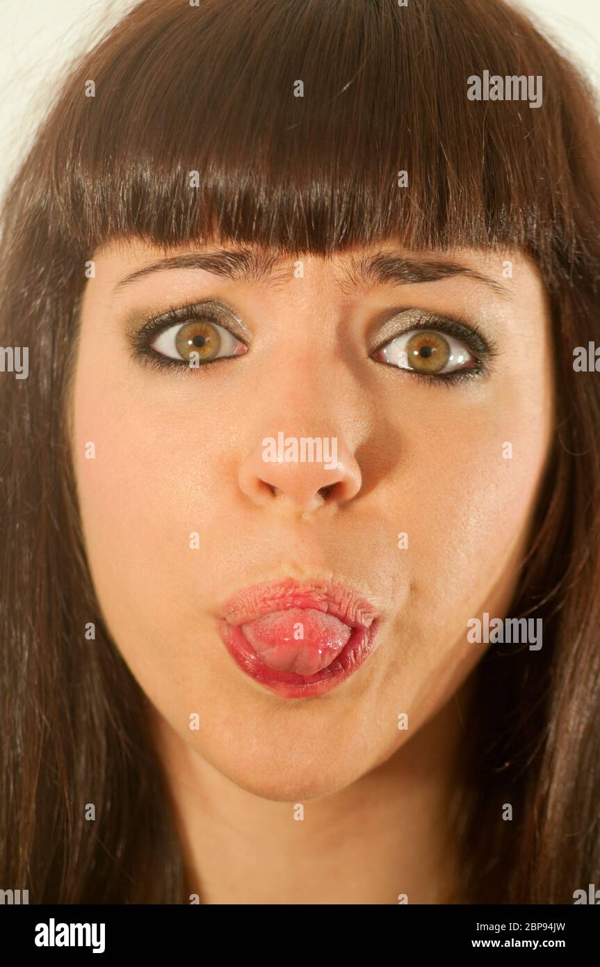 Jeune femme qui colle à la langue et regarde la caméra. Fermer la vue. Banque D'Images