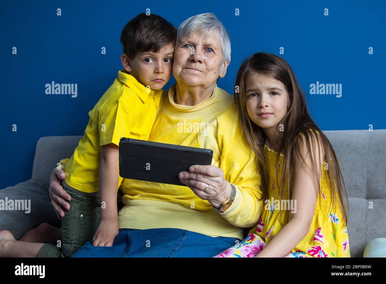 Une vieille grand-mère et ses petits-enfants bien-aimés s'assoient à la maison et parlent au téléphone Banque D'Images