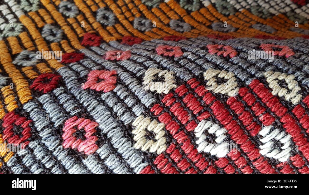 Plis de tissu tissé folk Craft avec motif losange texturé. Fond de tapis turc ornemental. Texture tissée de tapis colorés faits main. Banque D'Images