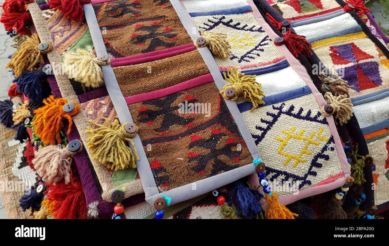 Pile de tapis traditionnels asiatiques faits main avec des glands colorés. Pile de petits tapis tissés. Ornements asiatiques traditionnels. Toile de fond du bazar turc Banque D'Images