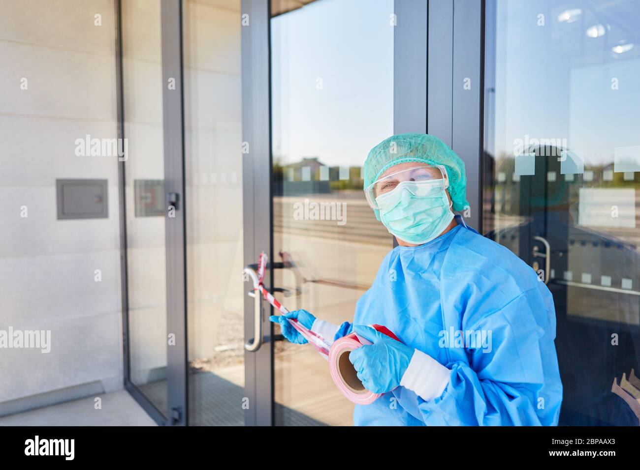 L'employé attache le cordon à la porte de la clinique fermée en quarantaine en raison du coronavirus et du Covid-19 Banque D'Images