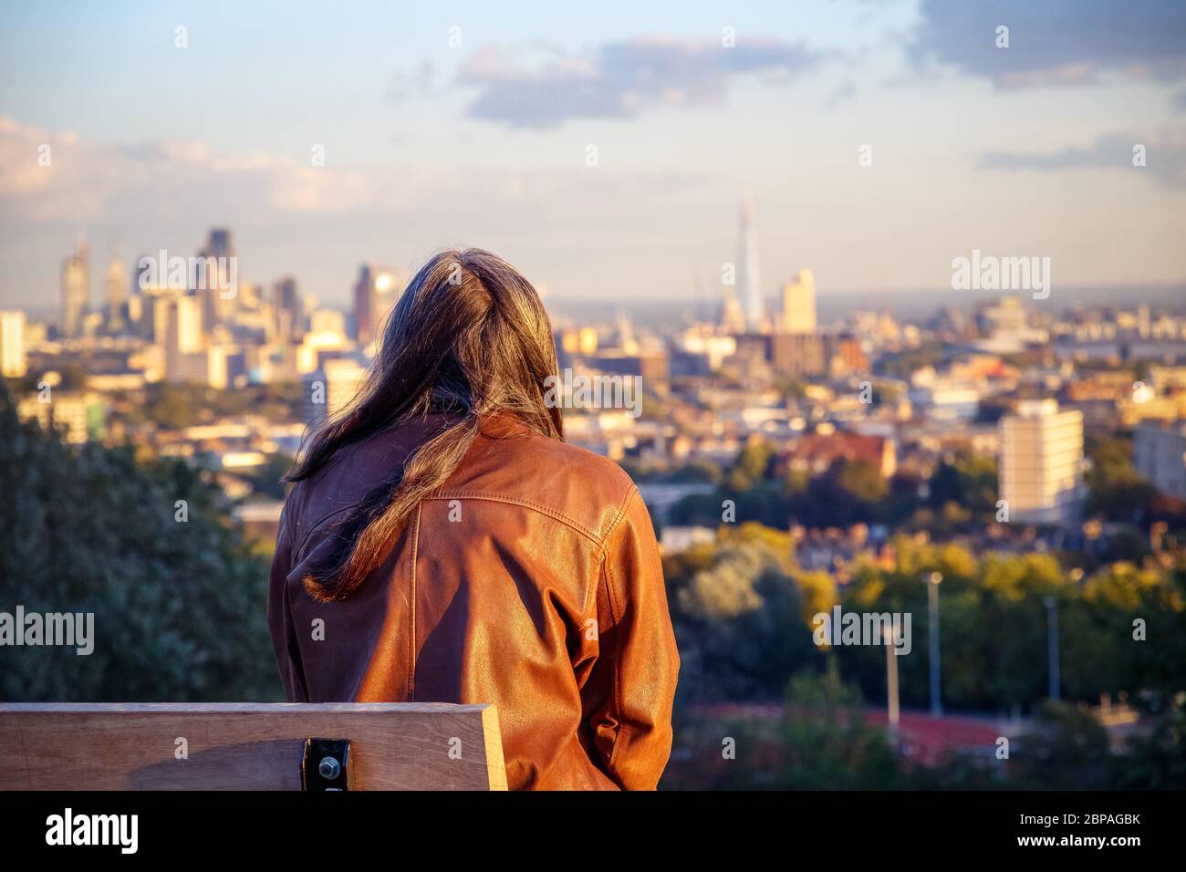 Vue arrière d'une femme assise sur un banc face à la ville de Londres depuis Parliament Hill à Hampstead Heath Banque D'Images