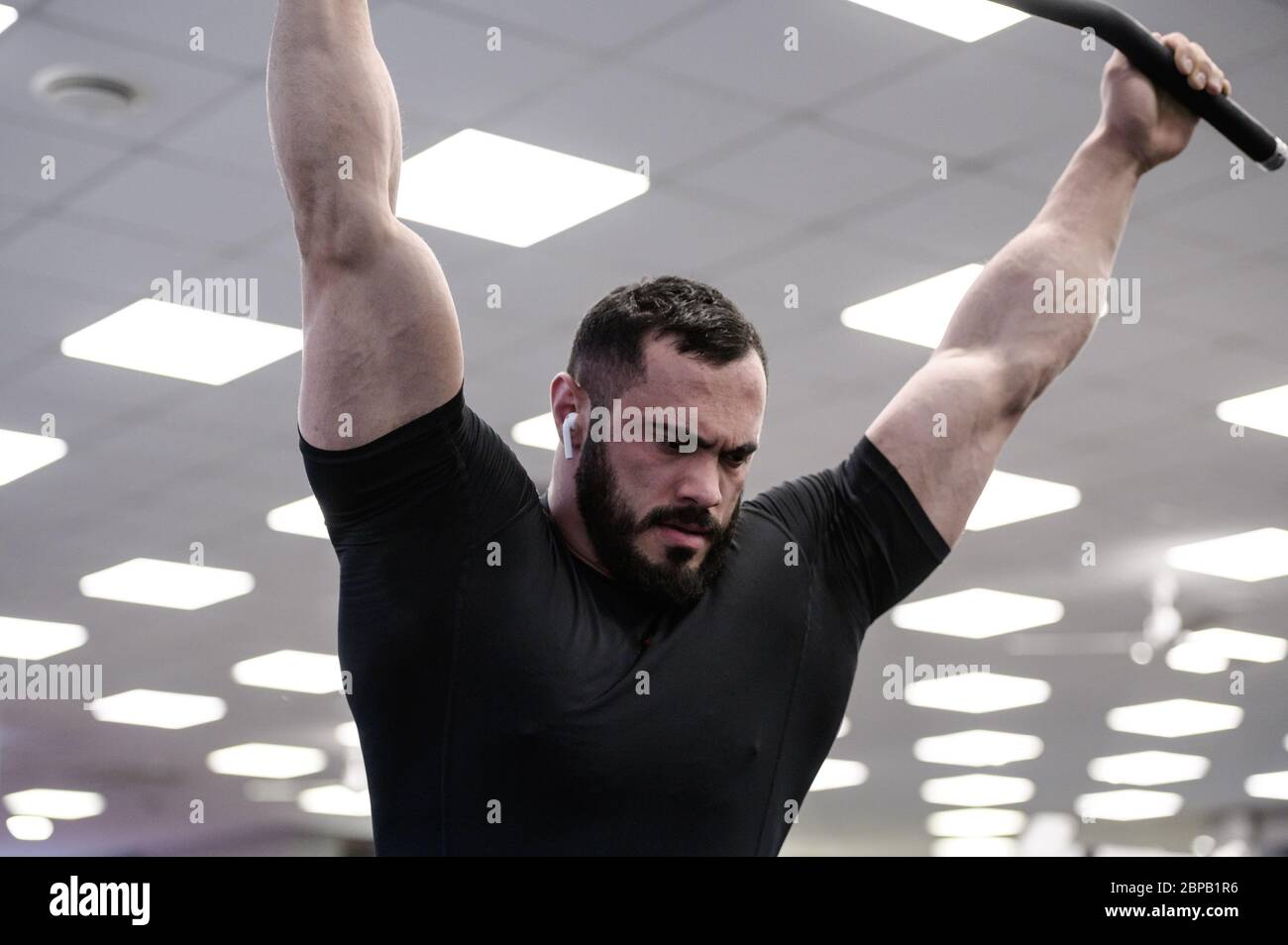 jeune homme barbu musclé en jersey noir pendant le repos dans la salle d'entraînement Banque D'Images