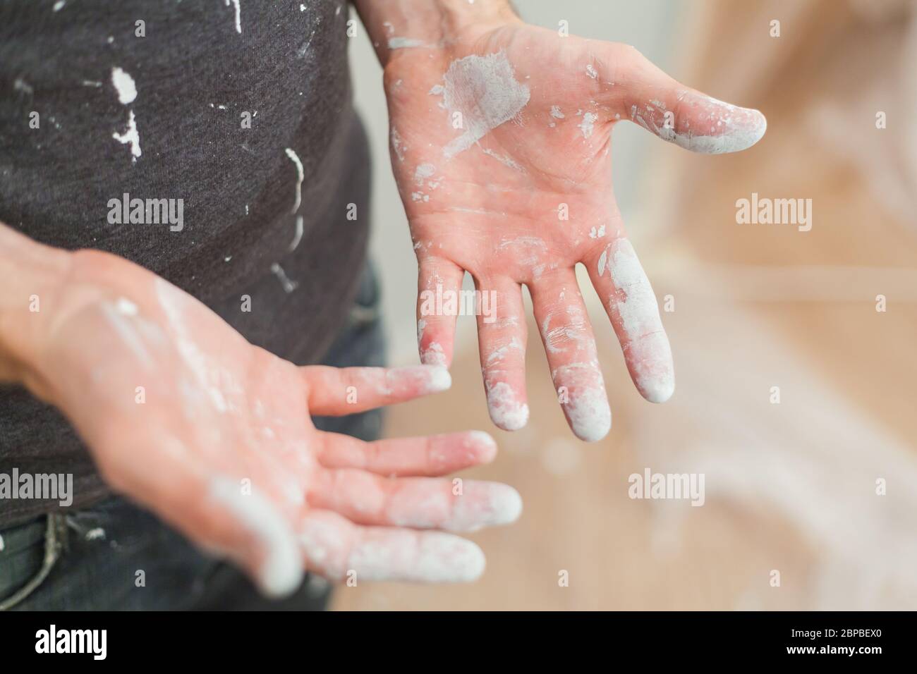 Artisan avec des particules de peinture blanche aux mains et aux vêtements après le travail de peinture rénovation sale travail de formation profession d'enseignement faites-le vous-même Banque D'Images