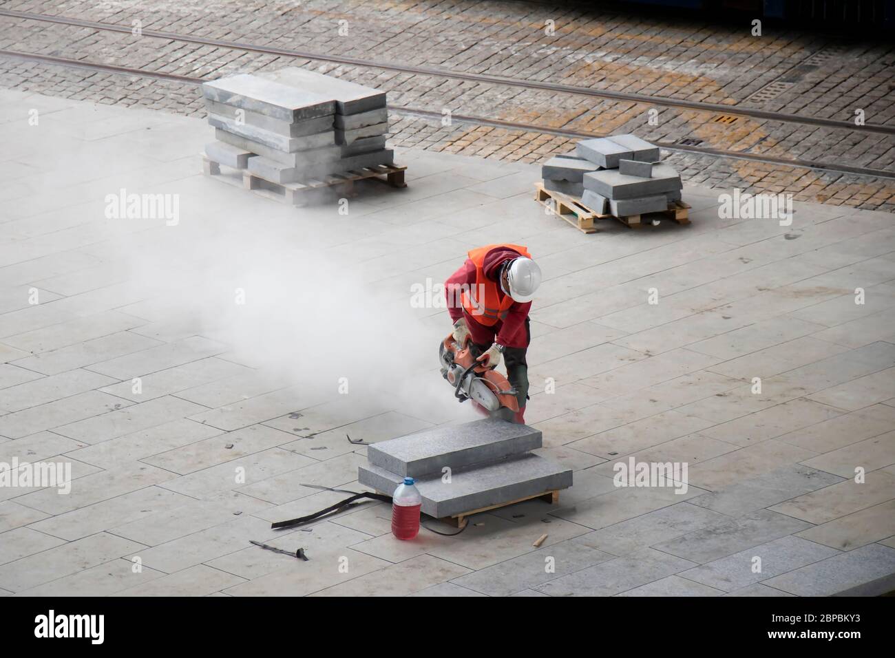 Belgrade, Serbie - 18 mai 2020 : ouvrier de la construction coupant des blocs de pavage avec fraise à disque pour pierre à essence, vue à angle élevé Banque D'Images