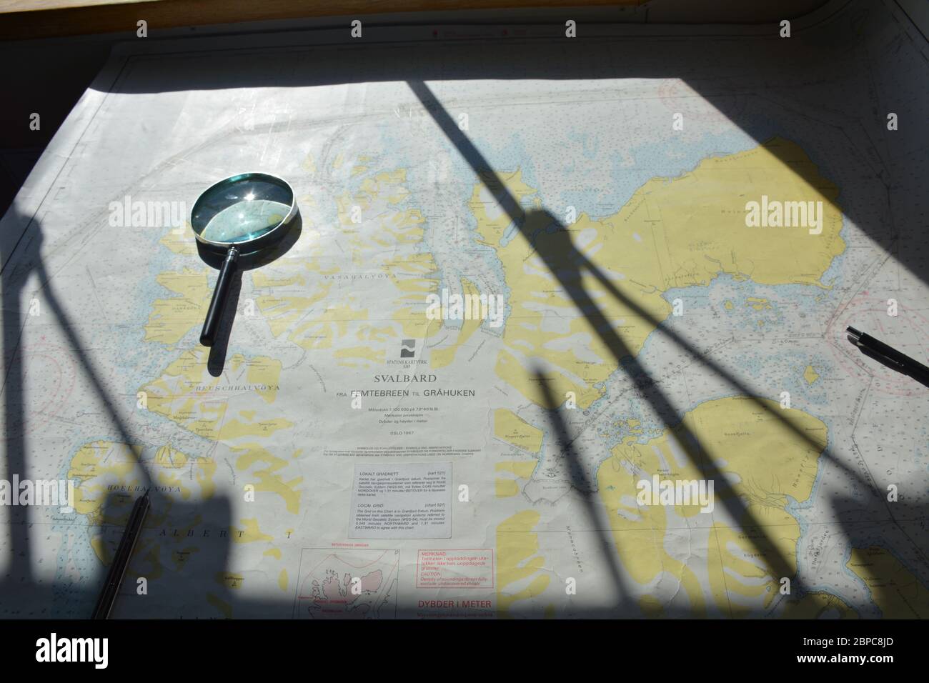 Cartes d'expédition et loupe à bord de l'Akademik Sergueï Vavilov, un navire de recherche russe affrété par une compagnie de croisière, à Svalbard Banque D'Images