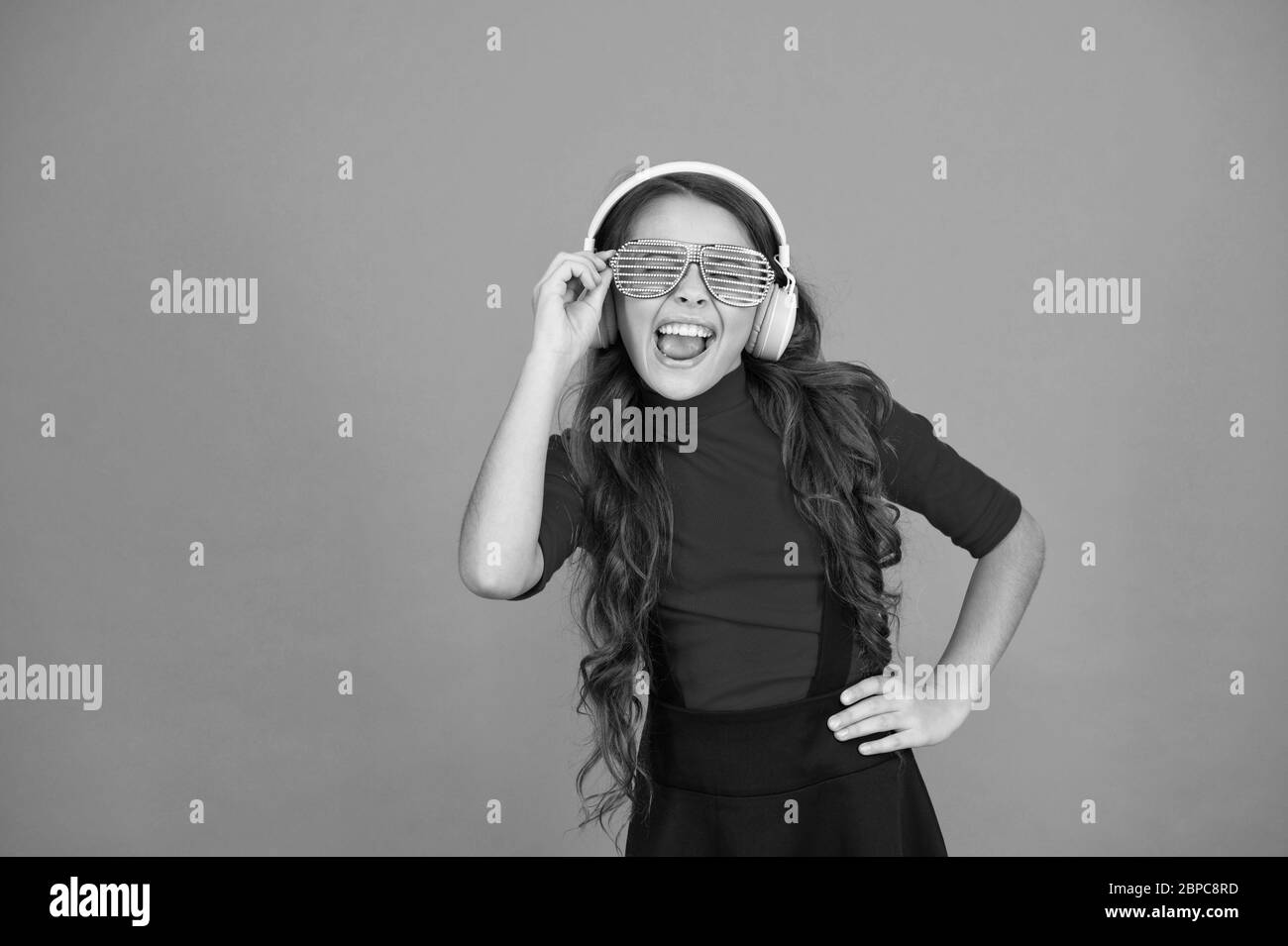 Piste froide. Fille avec lunettes arrière-plan orange. Événement et divertissement. Fille de fête. Accessoire de fête. Amuse-toi bien. Liste de lecture pour la fête. Concept de musique. Enfant porter des lunettes. Magasin de mode de lunettes. Banque D'Images