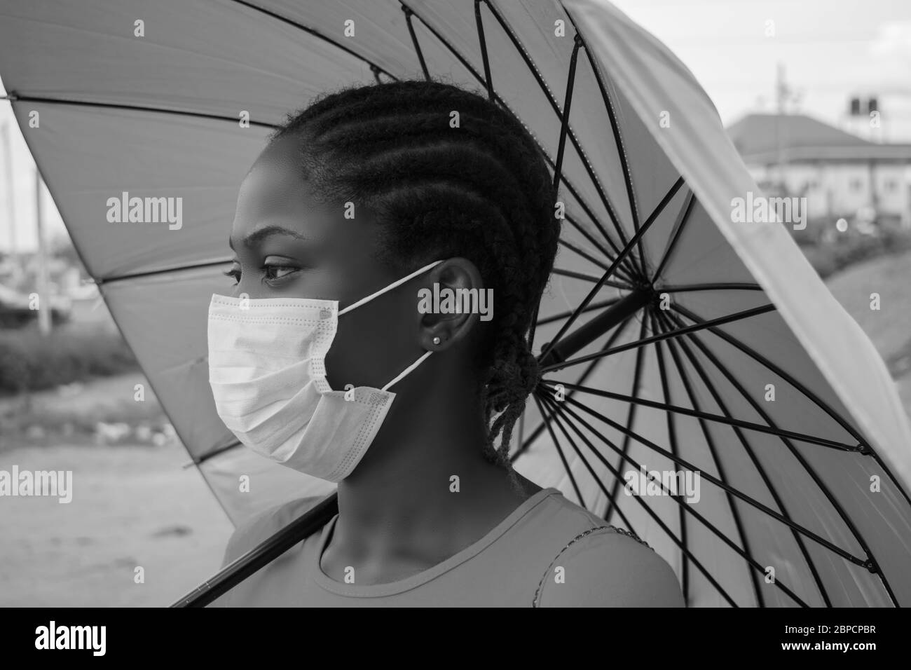 jeune belle femme africaine portant un masque pour prévenir, prévenir, se prémunir contre l'épidémie dans la société et tenir un parapluie Banque D'Images