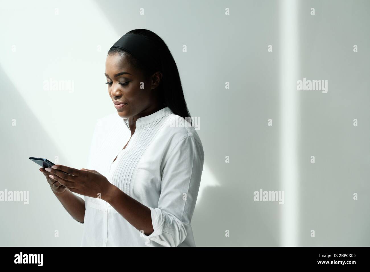 Femme noire utilisant un smartphone pour envoyer un message texte Banque D'Images
