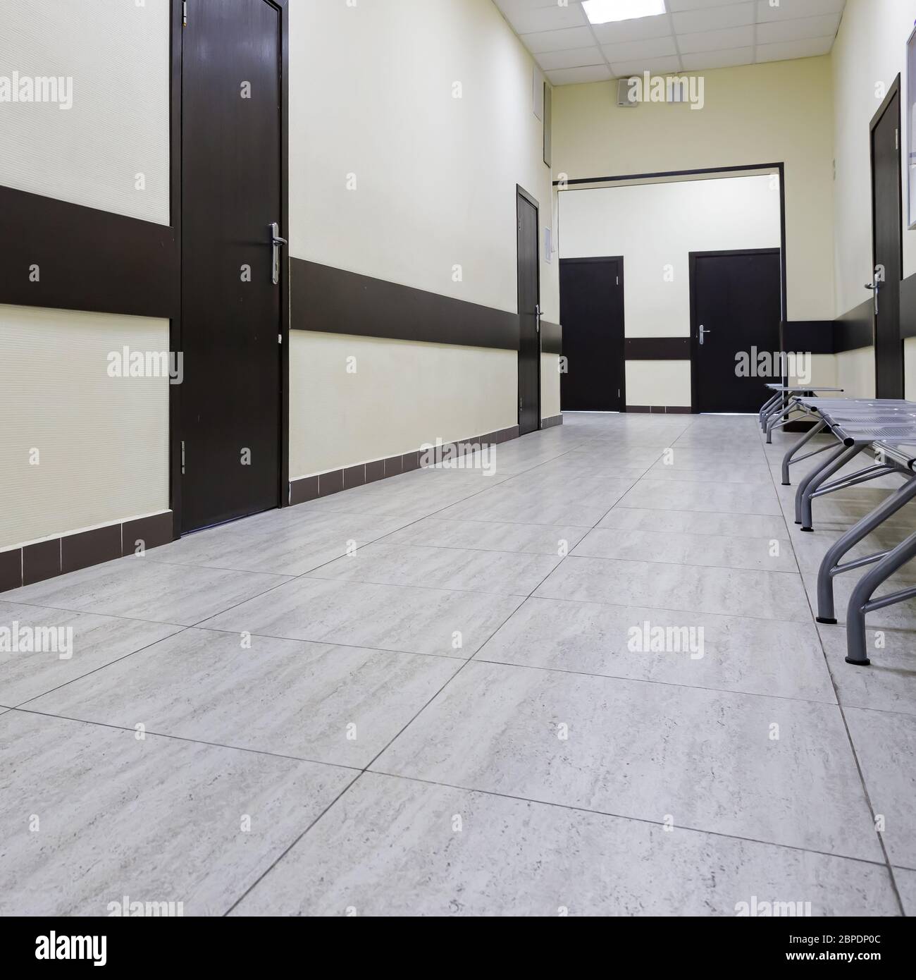 couloir vide dans le bâtiment moderne. Il y a de nombreuses portes brunes le long d'un très long couloir avec des murs beige. Banque D'Images