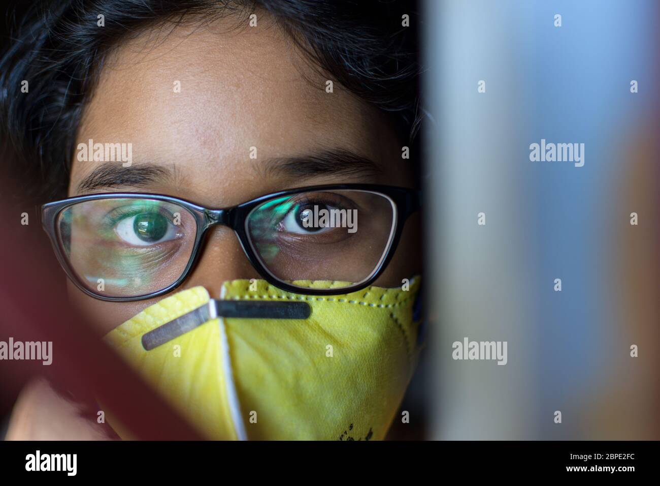 Une petite fille indienne reste à la maison en portant un masque facial pendant la quarantaine à domicile pour la pandémie de virus Corona COVID-19. Banque D'Images