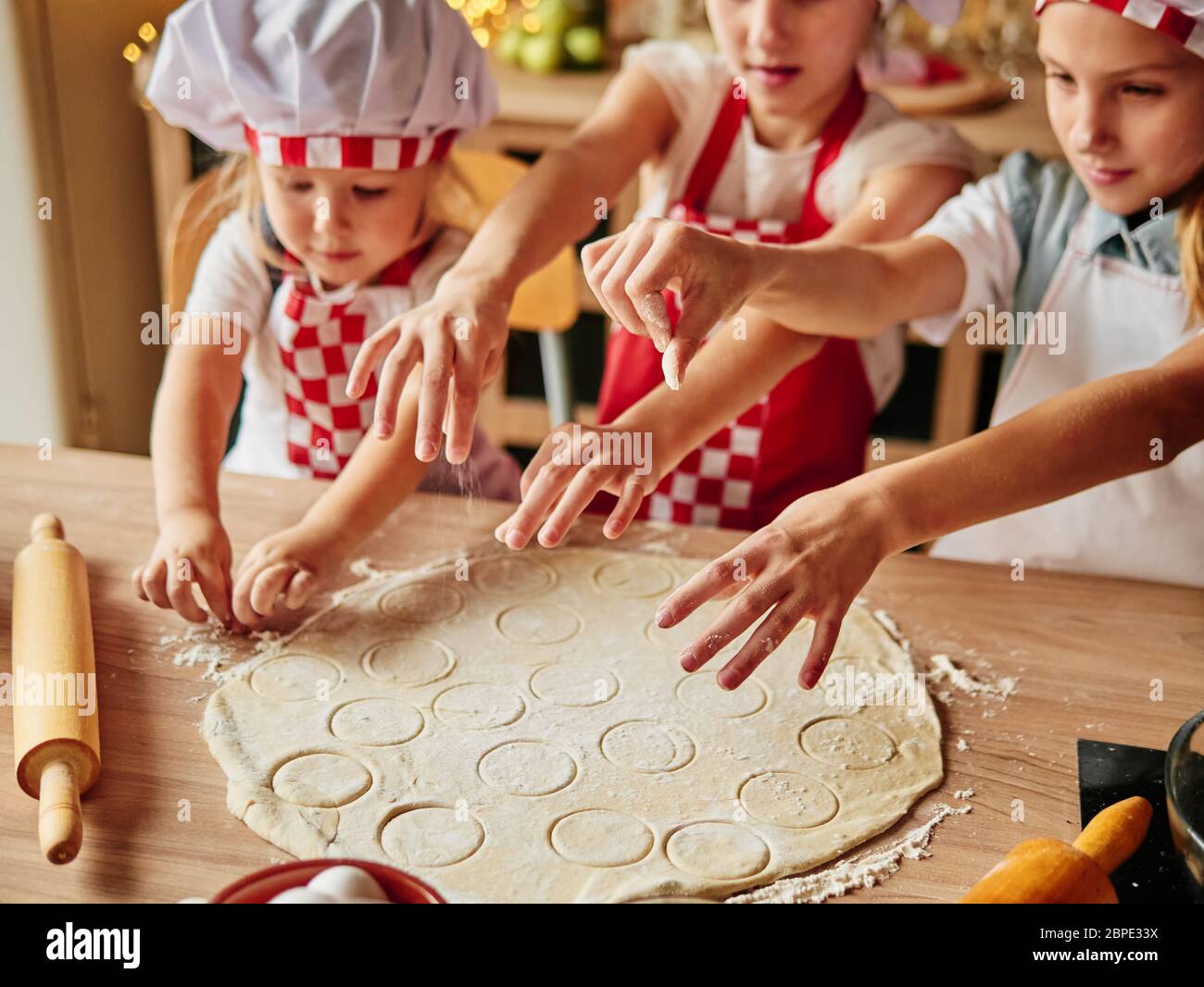 Trois petits chefs qui apprécient dans la cuisine font des gâteaux. Filles dans la cuisine. Ménage en famille. Banque D'Images