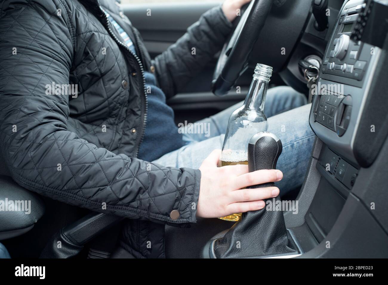 Une photo d'un jeune homme de boire de l'alcool au volant Banque D'Images