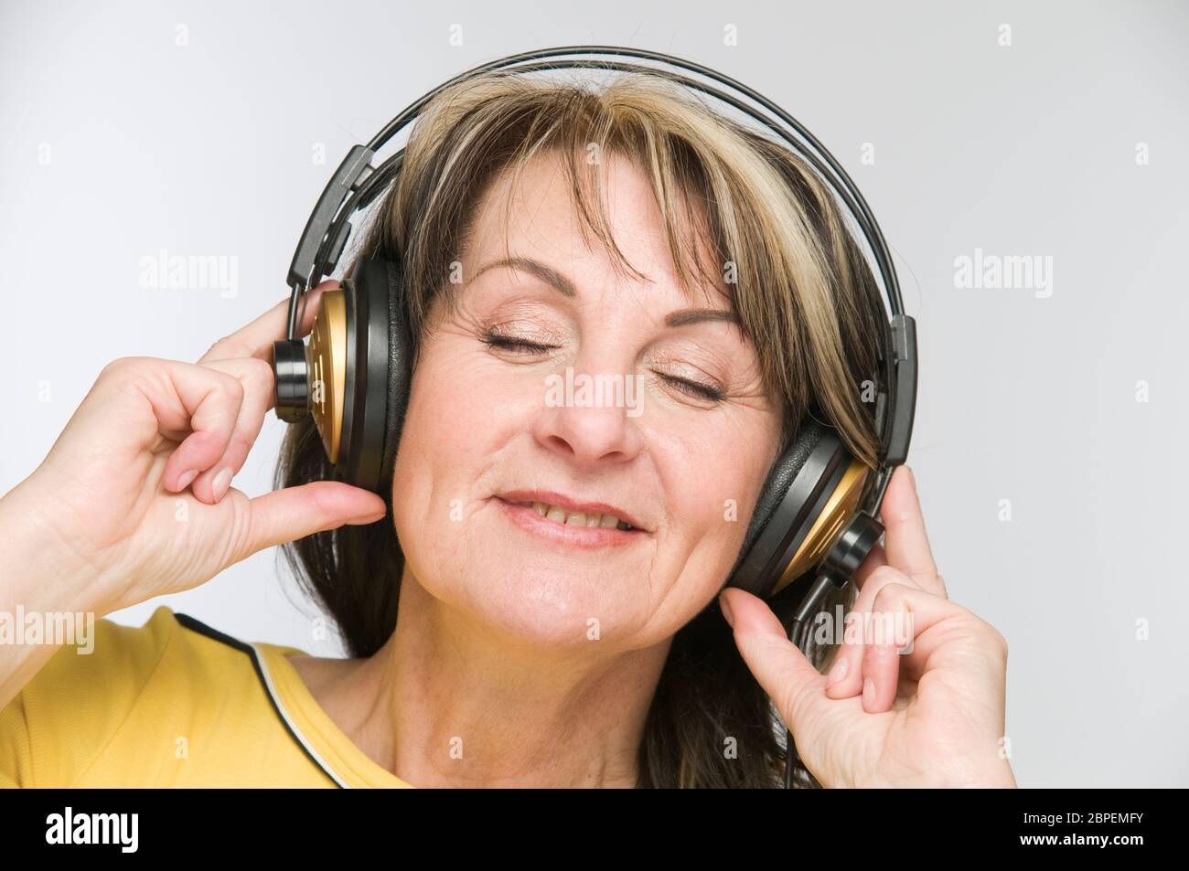 Kopf-und-Schulter-Ansicht einer Frau mit geschlossenen Augen modifie mittleren und vor Kopfhörern weißem Hintergrund. Banque D'Images