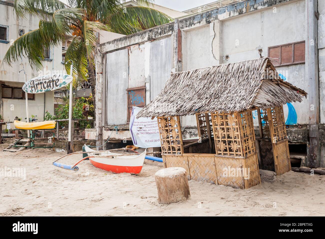 Une petite cabane de plage se trouve à l'extérieur d'un bâtiment abandonné sur la plage principale de la ville d'El Nido, Palawan, Philippines. Banque D'Images