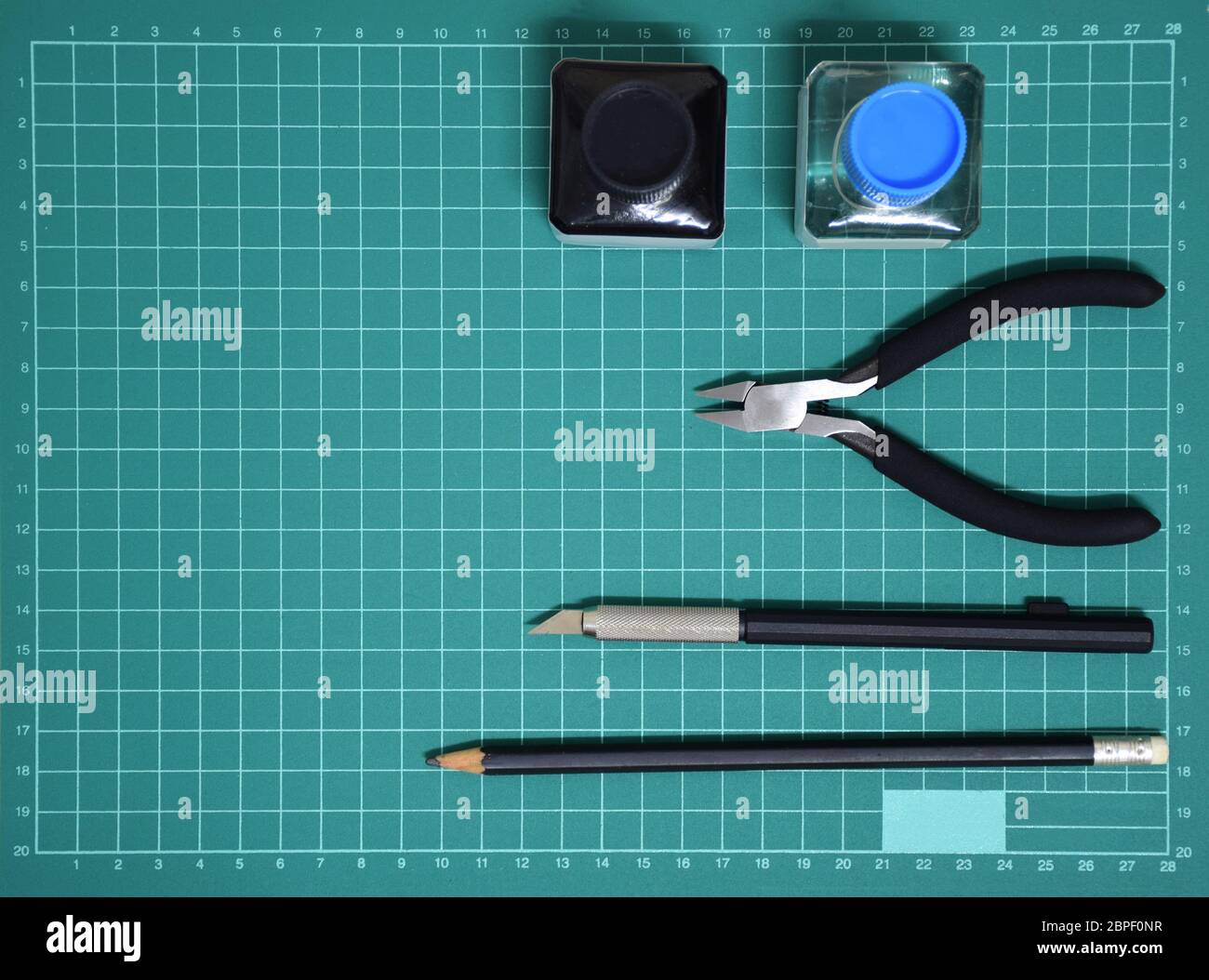 Vue du dessus Kit d'outils modèle en plastique encre, couteau d'art, pince coupante sur tapis de coupe et espace de copie Banque D'Images