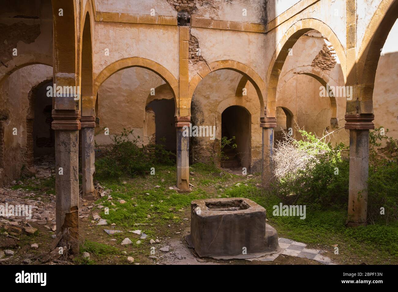 Un des nombreux chantiers dans une maison abandonnée. Arcade avec arcs sur une colonne. Base d'une ancienne fontaine. Herbe et plantes. Dar Caïd Hadji (également utilisé Hajji), Banque D'Images