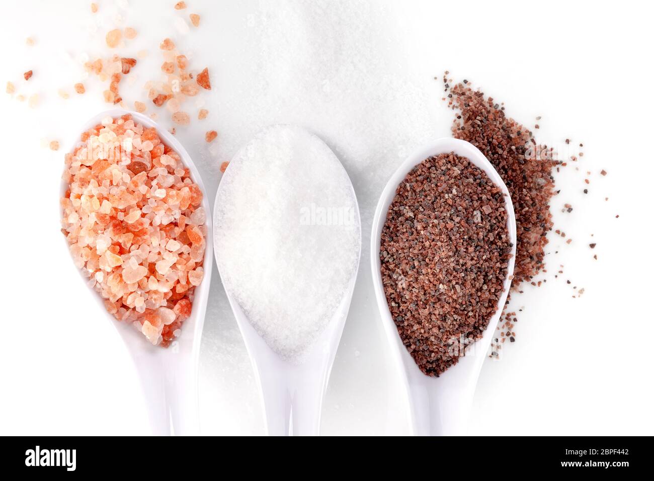 Différents types de sels dans les cuillères. Et de l'himalaya de sel de cuisine isolé sur fond blanc à partir de ci-dessus. Banque D'Images
