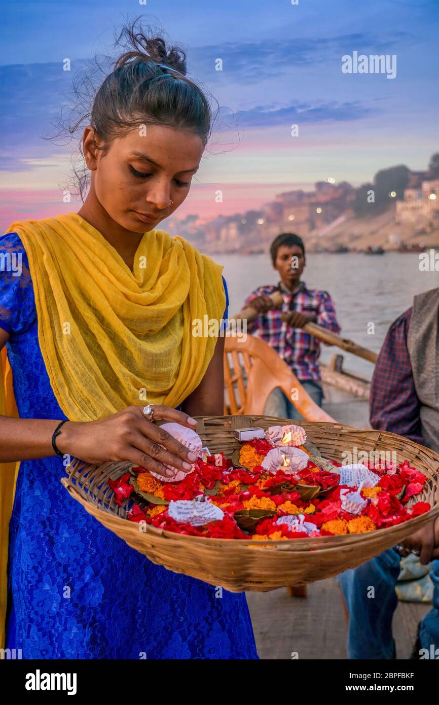 Varanasi, Inde - 11 novembre 2015. Une jeune femme indienne vend des fleurs et des bougies sur un bateau d'excursion au coucher du soleil sur le fleuve Ganges pendant le festival Diwali. Banque D'Images