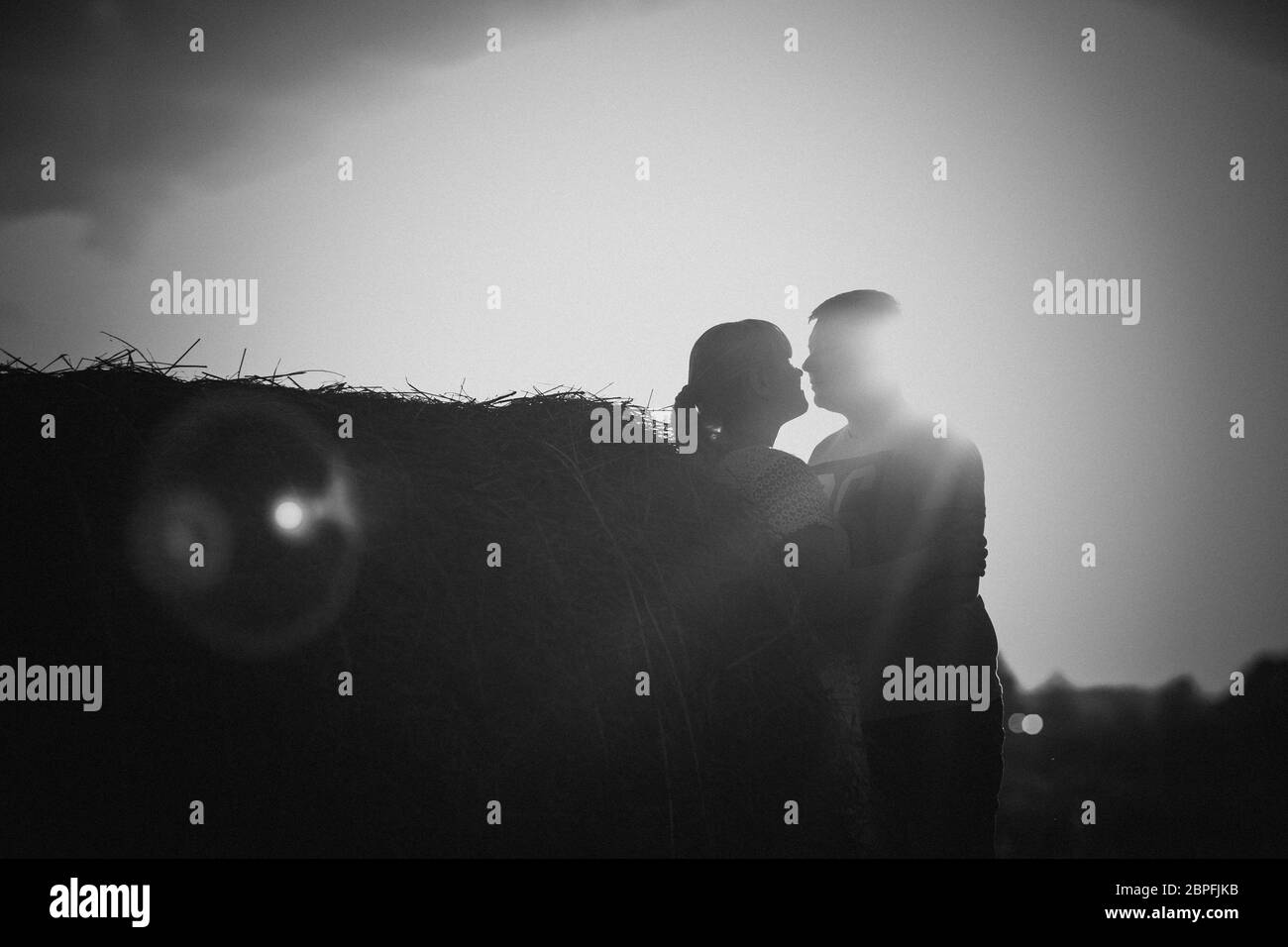 Silhouettes d'homme et femme sur un arrière-plan du soleil et sur le terrain. Banque D'Images